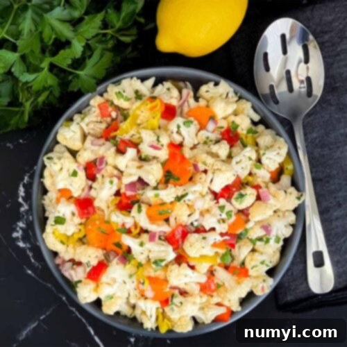 Marinated cauliflower salad in a dark bowl on a dark surface.