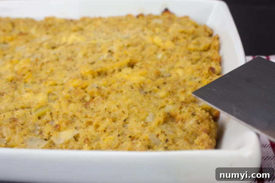 Golden-brown Southern cornbread dressing, freshly baked and still in its white casserole dish, showing off its crispy crust.