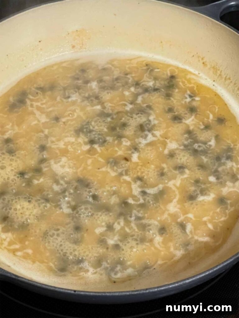 A piccata sauce cooking in a skillet.