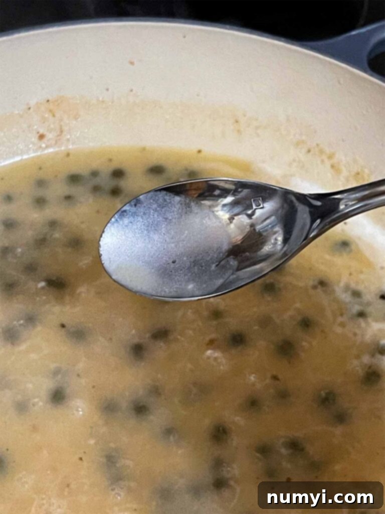 Piccata sauce cooking in a skillet.