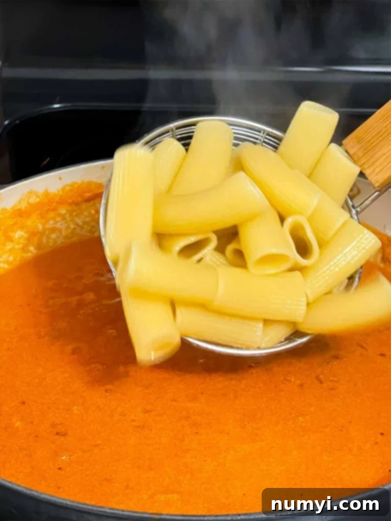 Adding pasta to Vodka sauce cooking in a skillet.