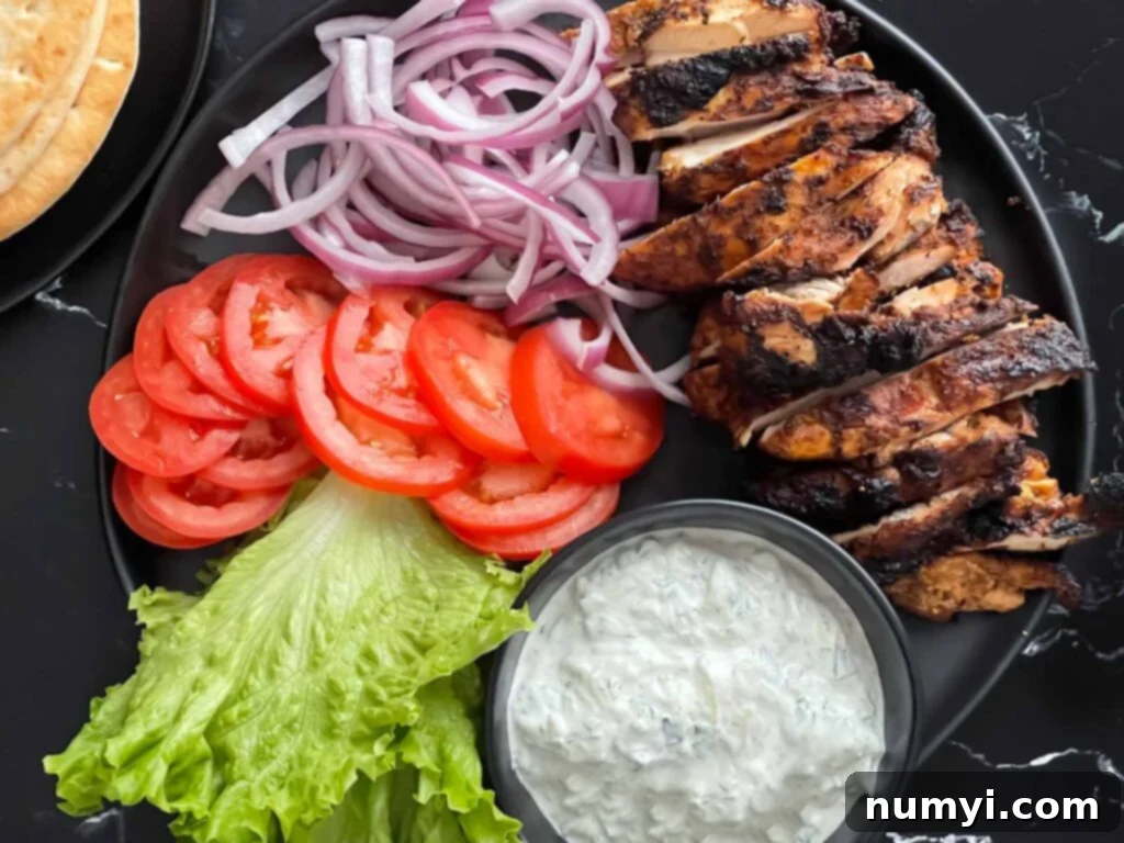 Perfectly grilled chicken shawarma pieces served on a dark plate, garnished with fresh herbs.