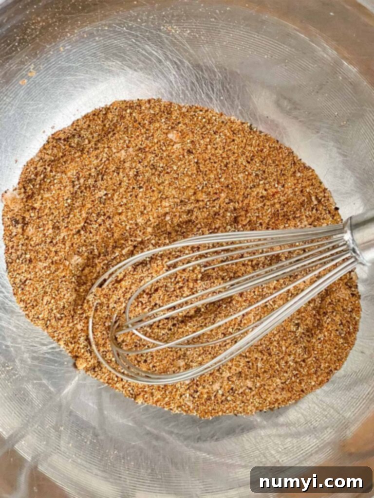 A close-up of various vibrant spices blended in a stainless steel bowl, creating the shawarma marinade base.