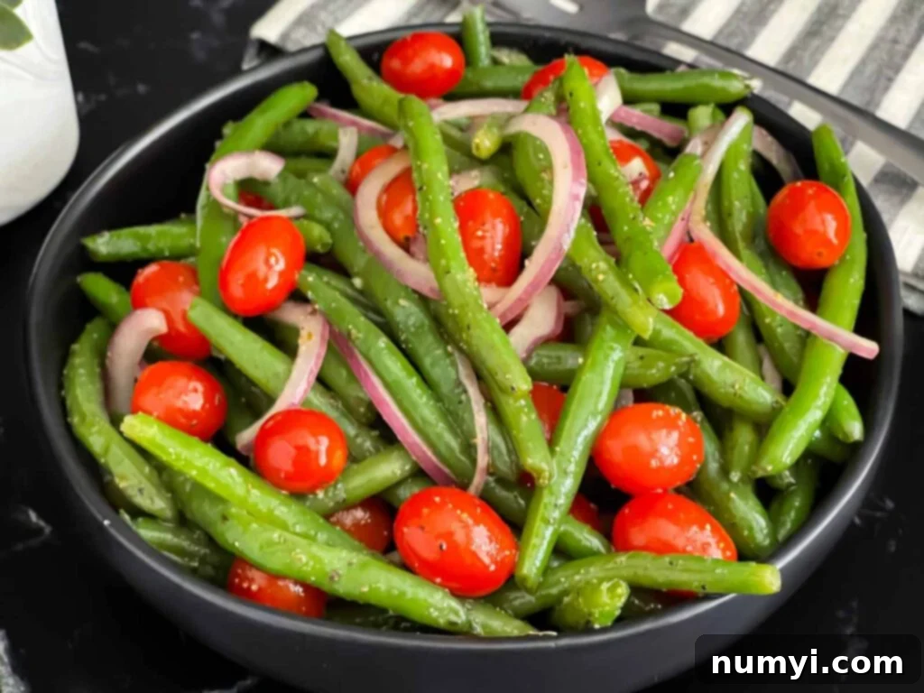 Italian green bean salad in a dark bowl on a dark surface.