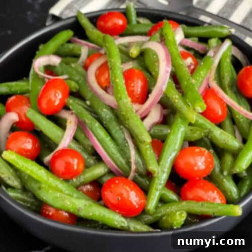 Italian green bean salad in a dark bowl on a dark surface.