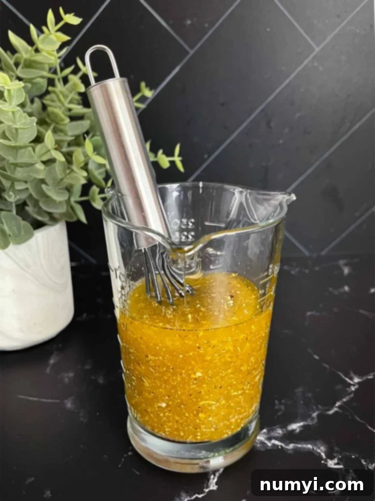 Italian green bean salad vinaigrette in a glass measuring cup on a dark surface.