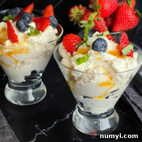 Ricotta mousse in a stemless martini glass garnished with strawberries, blueberries, basil, and honey.
