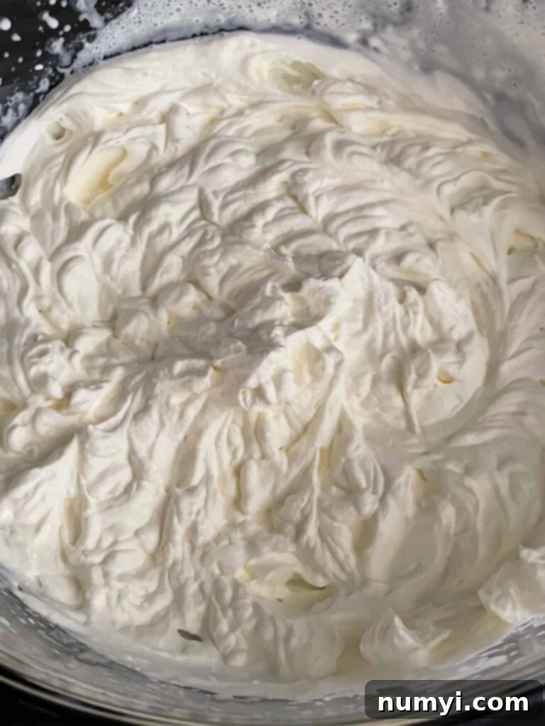 Whipped heavy cream in a glass mixing bowl.