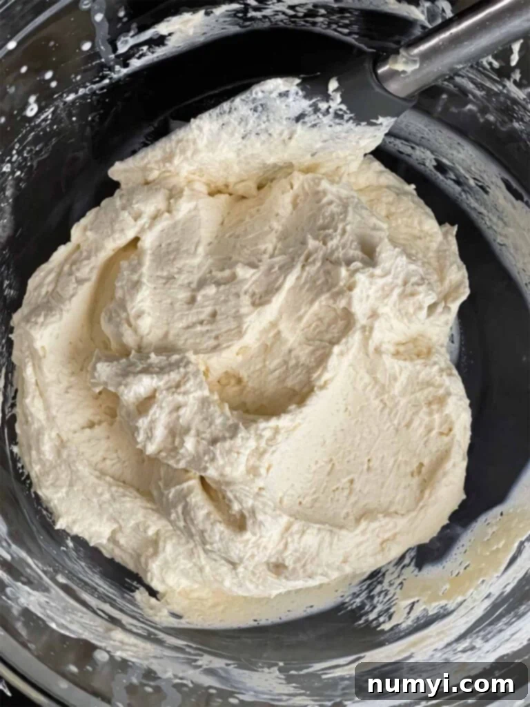 Ricotta mixture folded into the whipped cream in a glass mixing bowl.