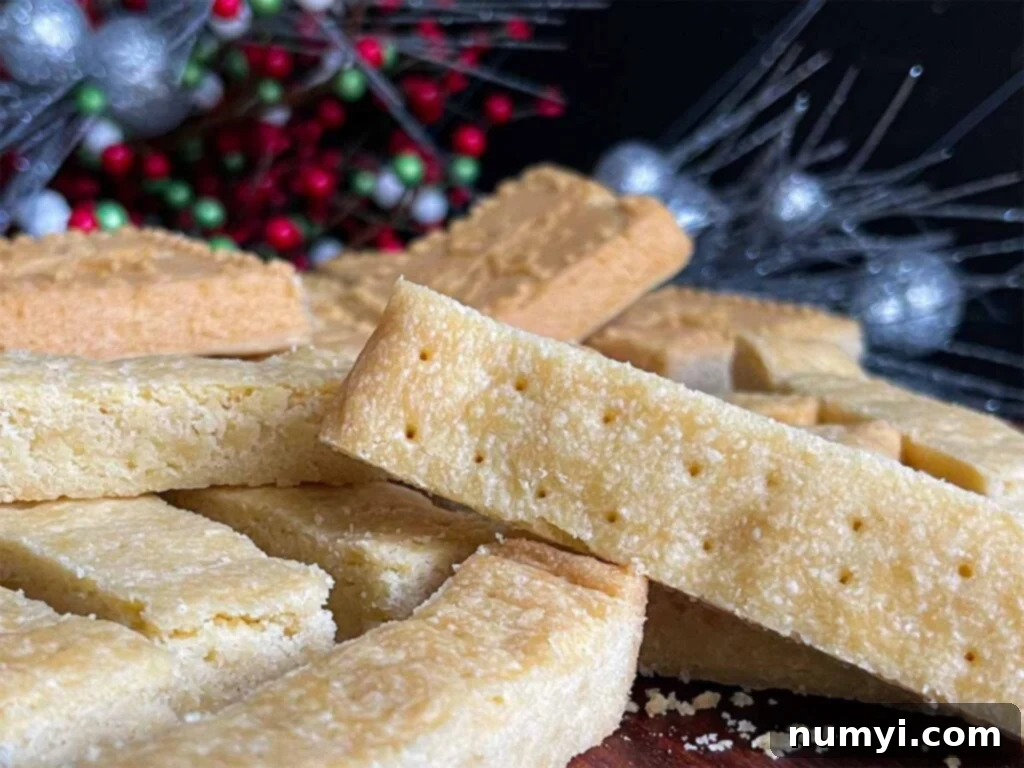 Classic shortbread cookies in stick shape and shortbread pan shape on a wooden cutting board.