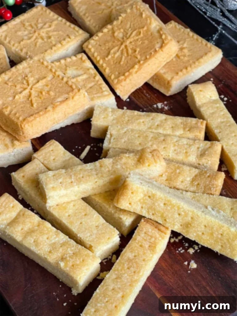 Classic shortbread cookies in stick shape and shortbread pan shape on a wooden cutting board.