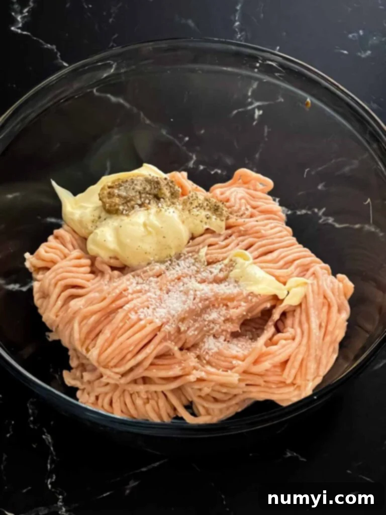 Zesty Carolina Grilled Chicken Burgers 13 Ground chicken mixed with other ingredients in a glass bowl.