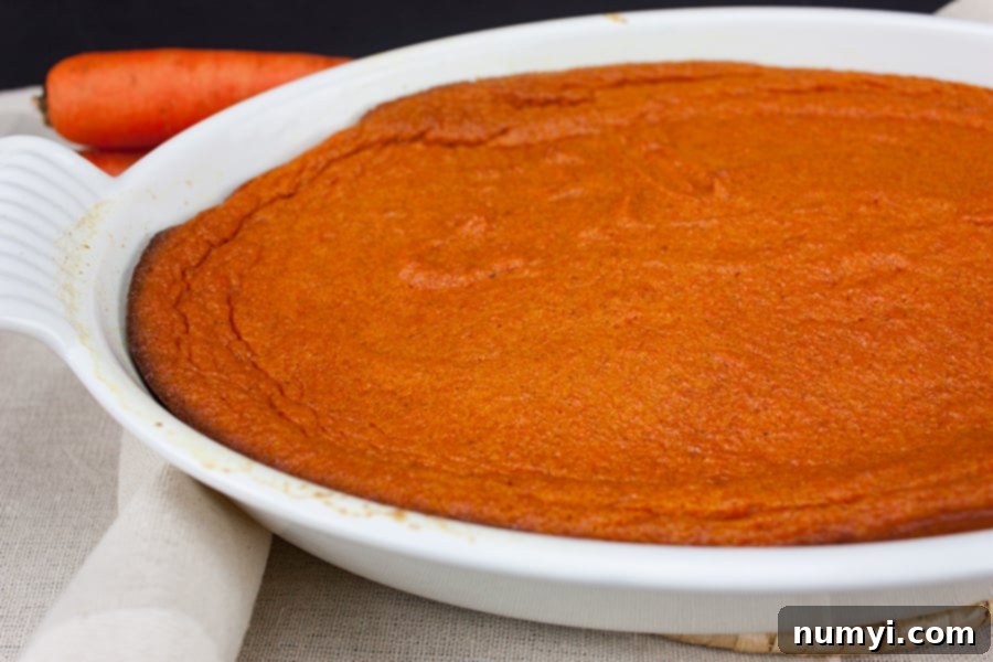 Carrot souffle in a white casserole dish, garnished with a dusting of powdered sugar.