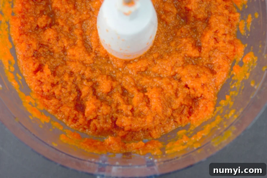 Carrots pureed in the bowl of a food processor, a key step for smooth carrot souffle.
