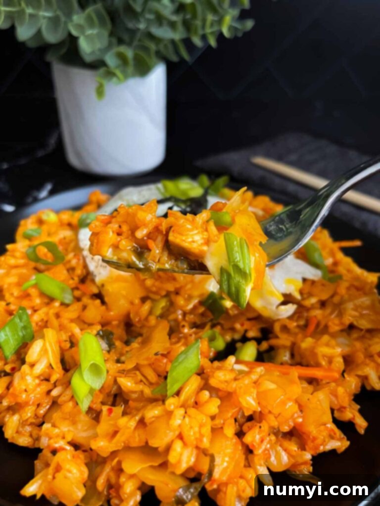 A fork piercing into a delicious portion of kimchi fried rice, ready to be enjoyed.