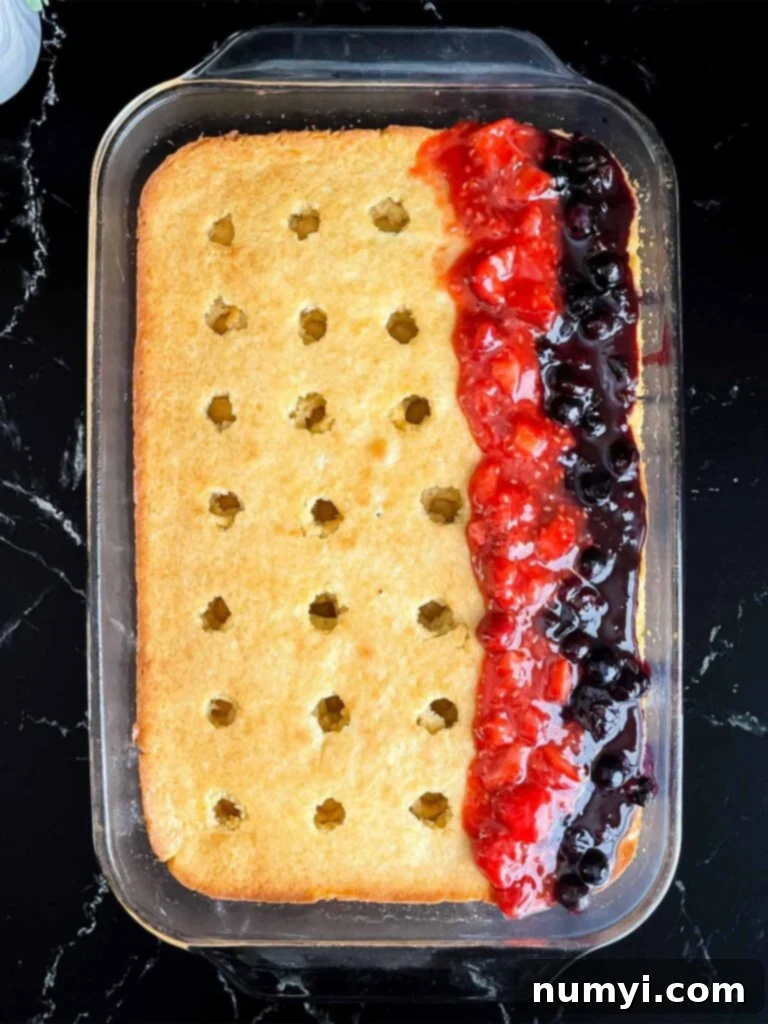 Luscious Berry Poke Cake 11 The poke cake being filled with alternating strips of vibrant blueberry and red berry filling, creating a beautiful pattern.