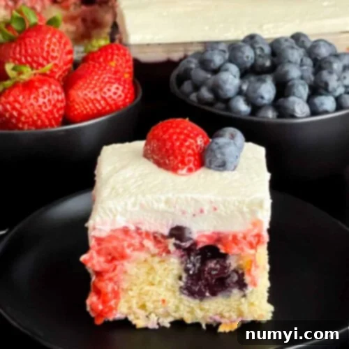 Luscious Berry Poke Cake 14 A slice of berry poke cake on a dark plate, showing its layers.