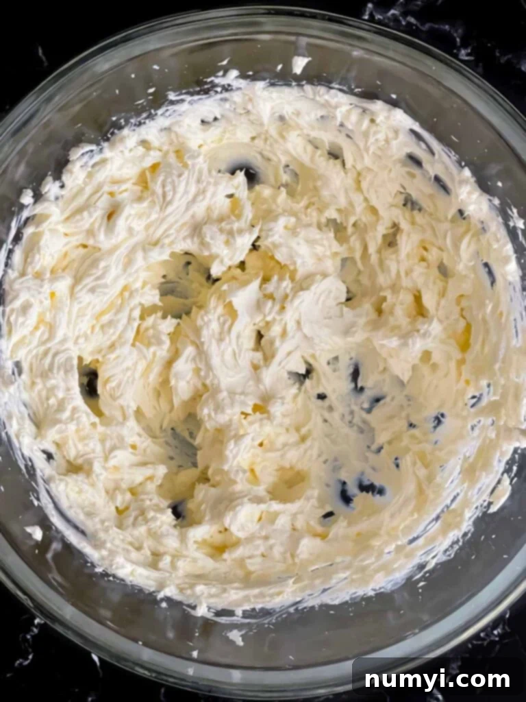 The cream cheese for the olive cheese ball beaten until smooth and creamy in a glass mixing bowl.