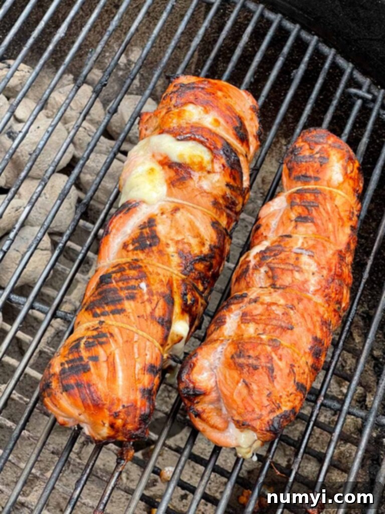 Cuban pork tenderloin roulade grilling over open flames on a barbecue.
