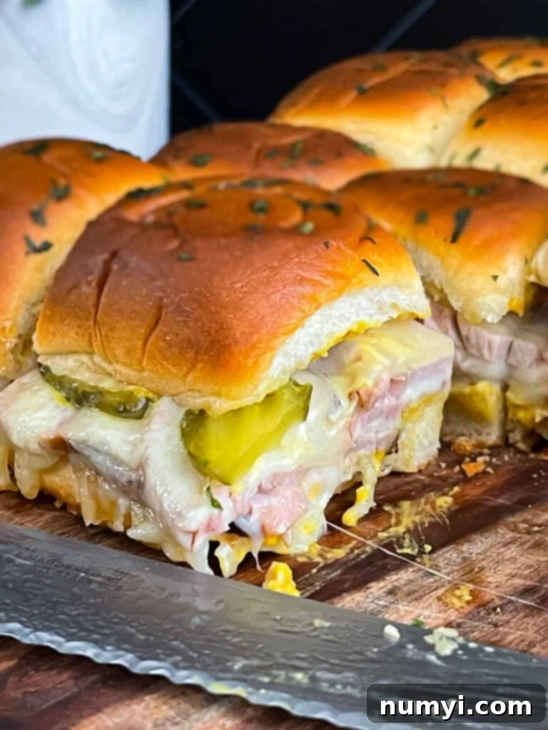 Freshly baked roll-cut pork tenderloin Cuban sliders cooling on the baking sheet.