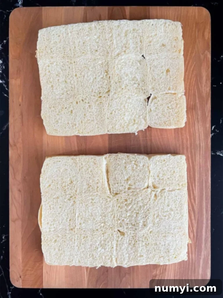 Slider buns neatly sliced in half, ready for assembly on a wooden cutting board.