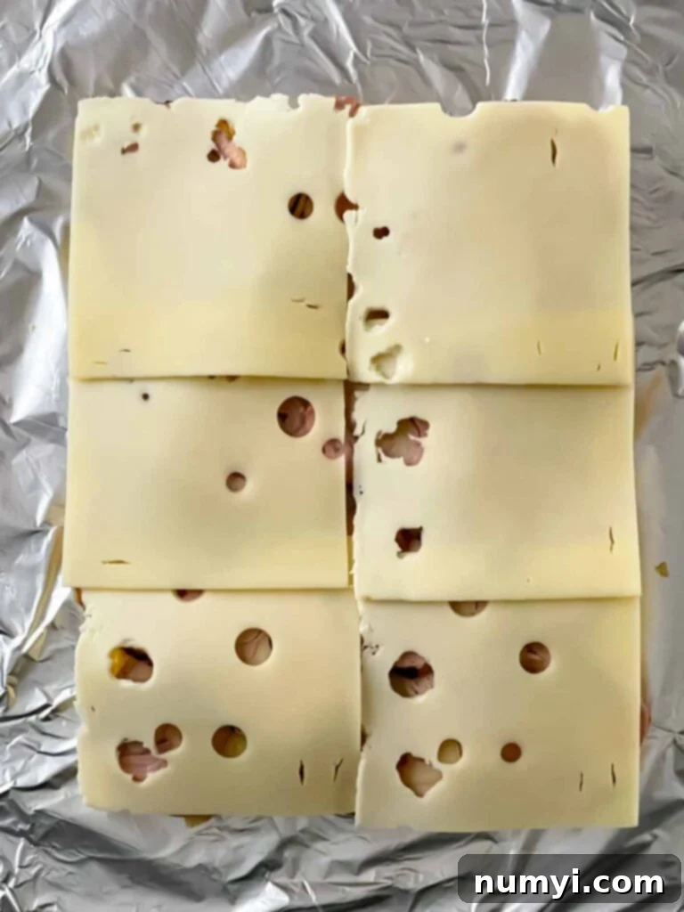 Sliced Swiss cheese being placed on top of the pork tenderloin for the Cuban sliders.