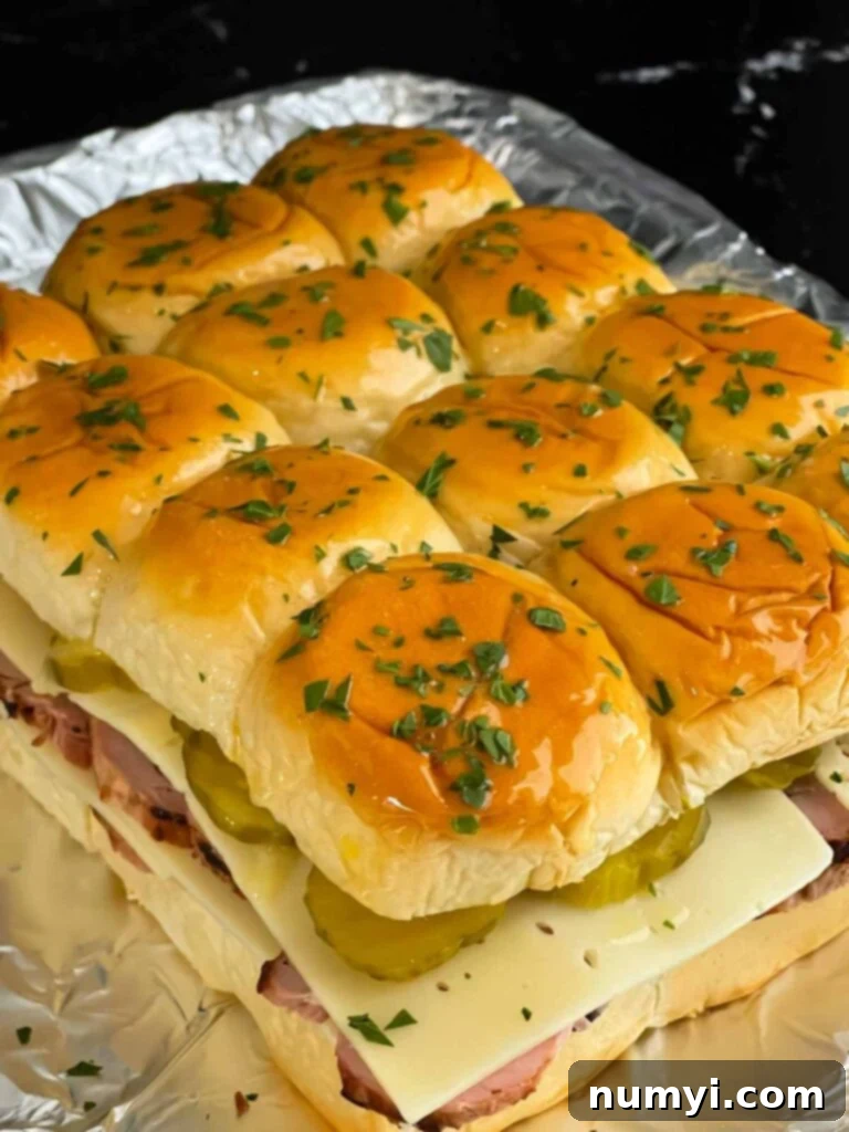 Buttered tops of Cuban sliders sprinkled with chopped parsley, awaiting baking.