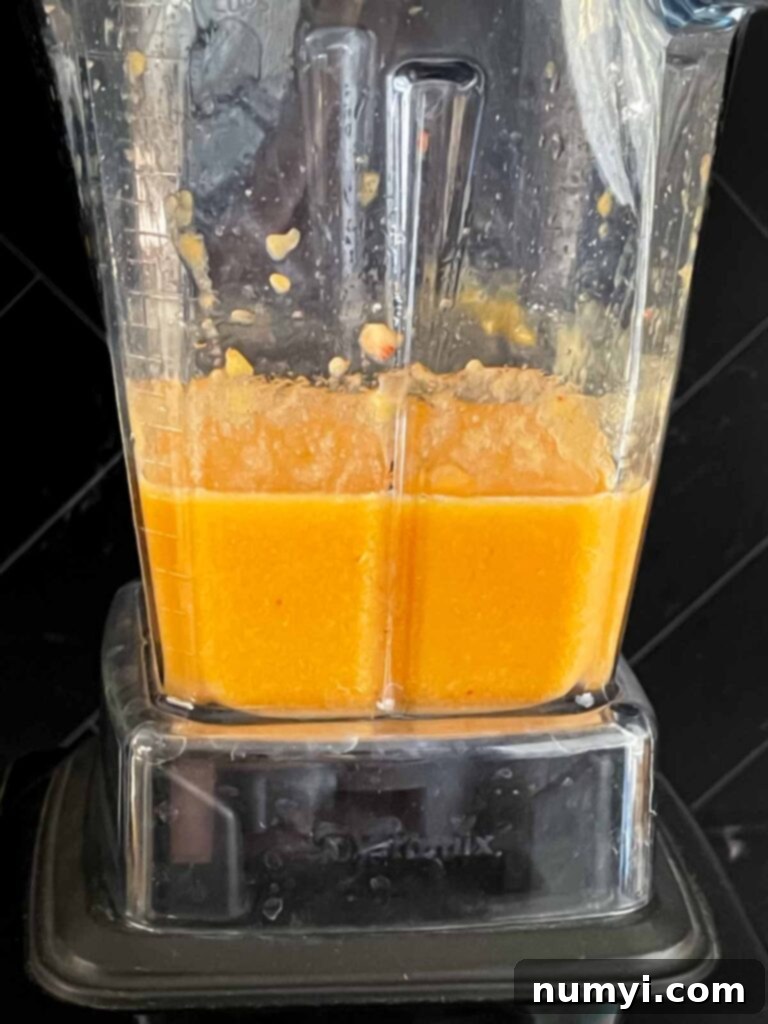 Fresh peach puree being blended in a blender on a dark surface.