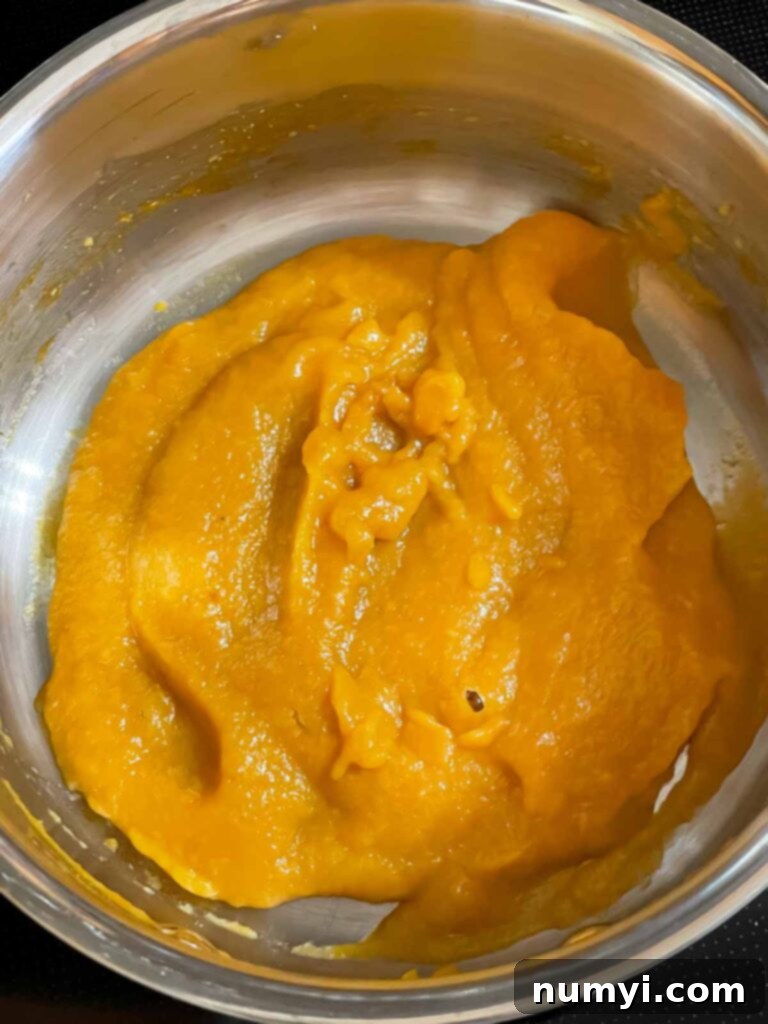 Reduced peach puree simmering in a small saucepan.