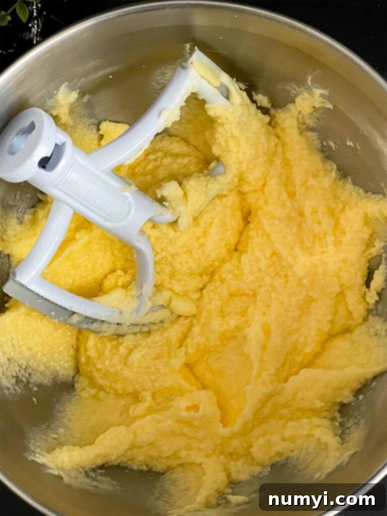 Eggs added to the peach pound cake batter in a metal mixing bowl.