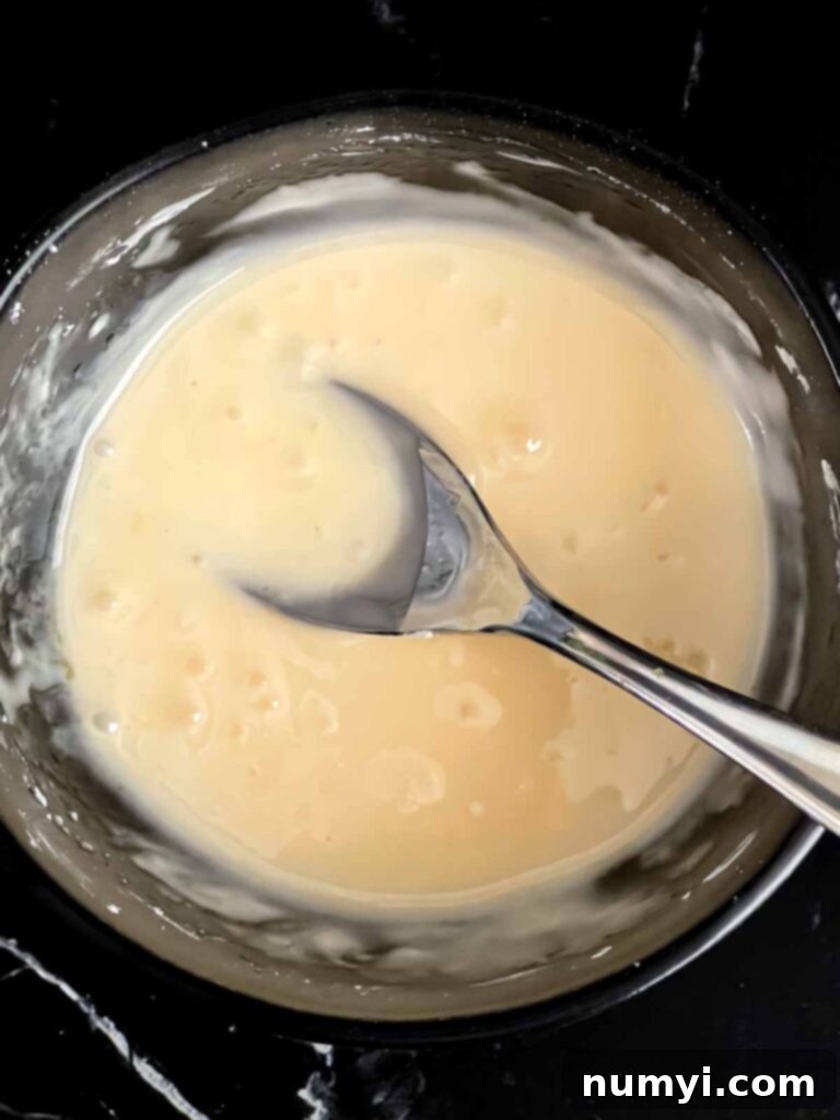 Peach glaze mixed in a small dark bowl, ready to be drizzled over the cake.