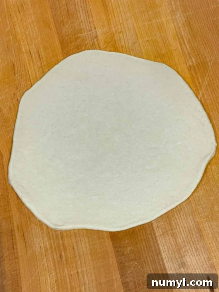 Hearty Italian Sausage Calzone 14 A circular piece of calzone dough, perfectly rolled out to an even thickness, ready for filling.