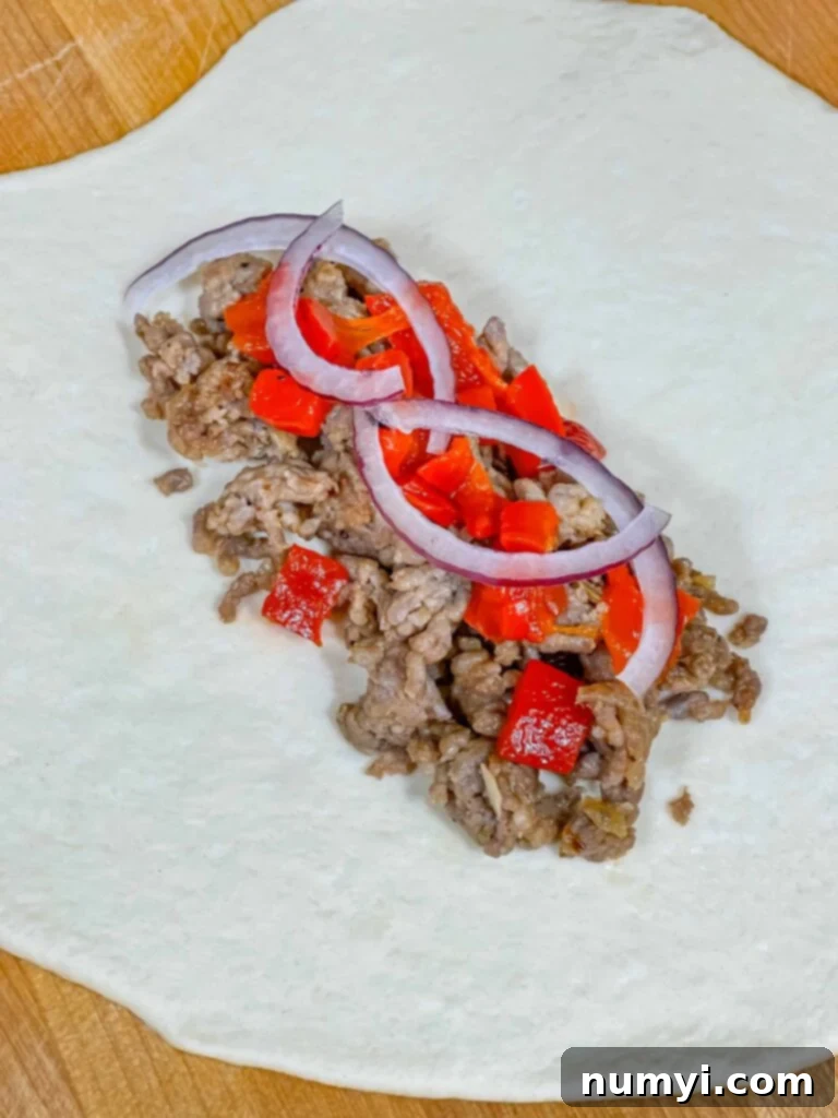Hearty Italian Sausage Calzone 15 The initial stage of assembling a calzone, with Italian sausage and vegetables carefully placed on one half of the rolled-out dough.