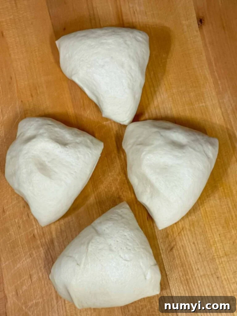 Hearty Italian Sausage Calzone 5 Four portions of pizza dough, perfectly divided and ready for shaping into calzones, laid out on a lightly floured surface.