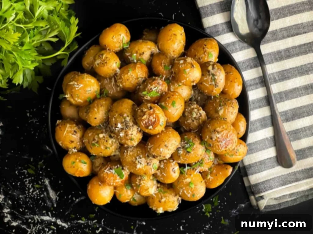 Ultimate Slow Cooker Garlic Parmesan Potatoes 2 Slow cooker garlic parmesan potatoes in a dark bowl garnished with parsley and parmesan cheese.