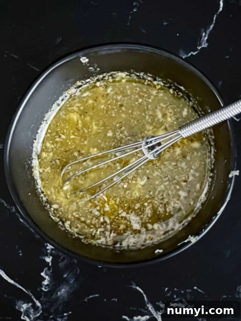 Ultimate Slow Cooker Garlic Parmesan Potatoes 4 Slow cooker garlic parmesan potatoes herb butter mixture in a dark bowl on a dark surface.
