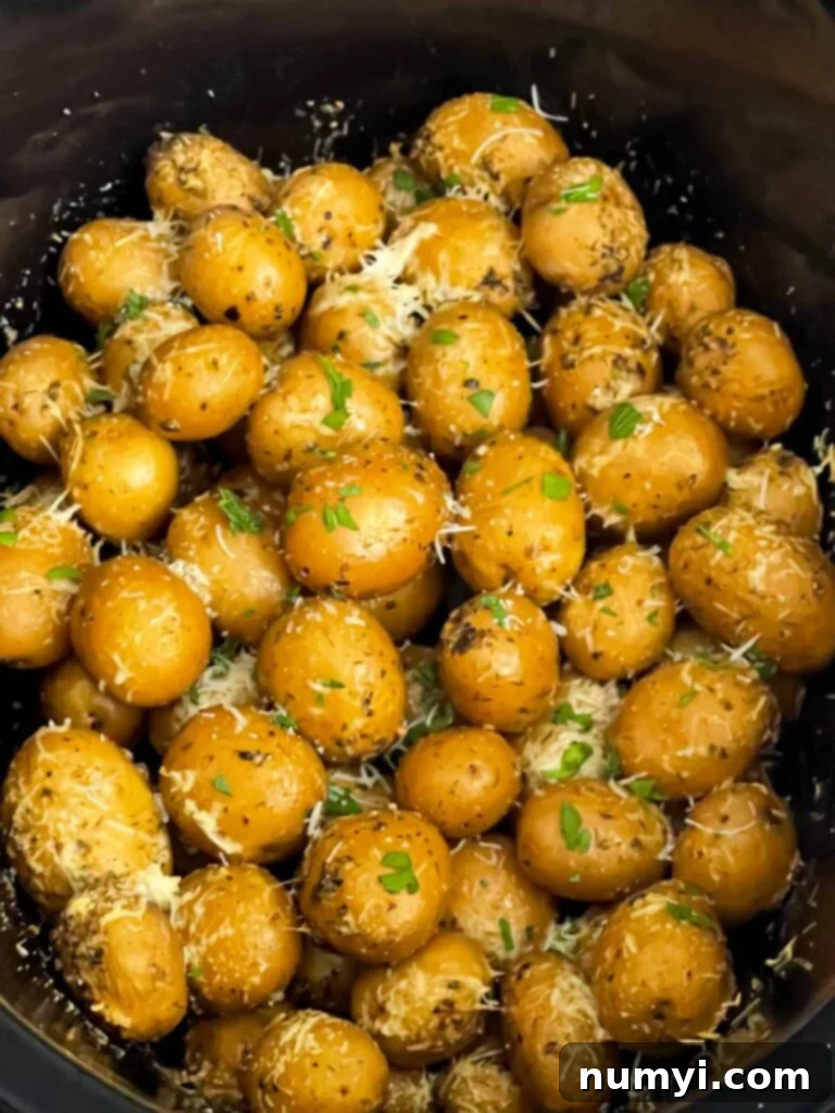 Ultimate Slow Cooker Garlic Parmesan Potatoes 6 Cooked garlic parmesan potatoes in the crock of a slow cooker.