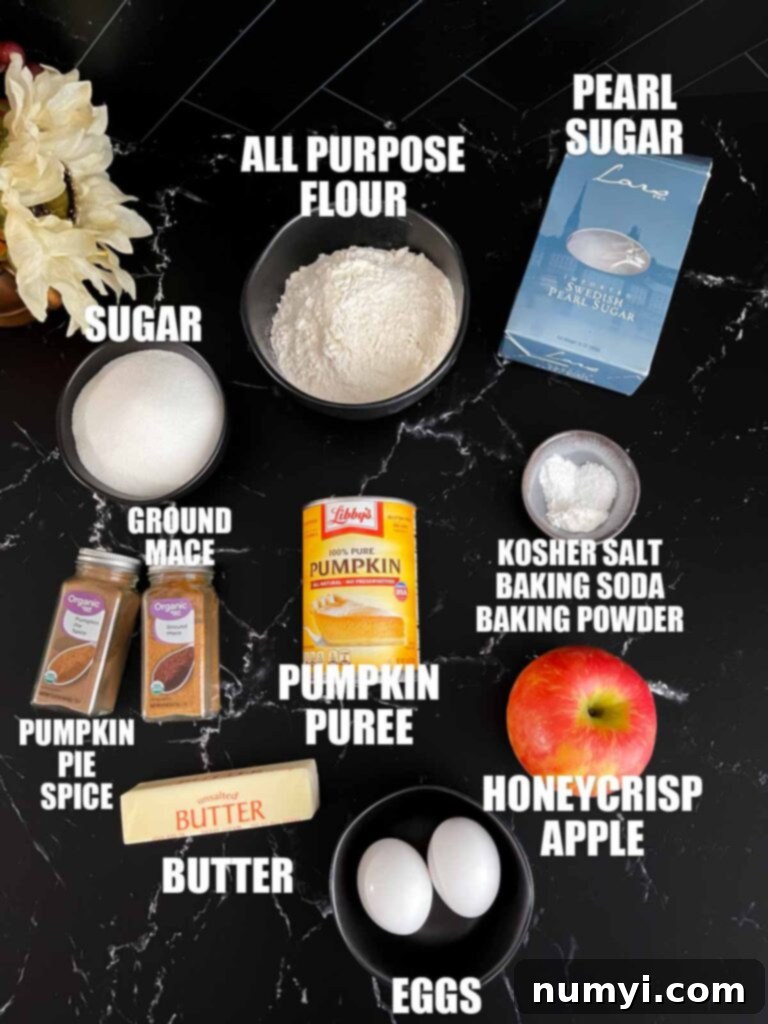 Various ingredients for pumpkin apple muffins laid out on a dark wooden surface, including flour, spices, pumpkin puree, eggs, and shredded apple.