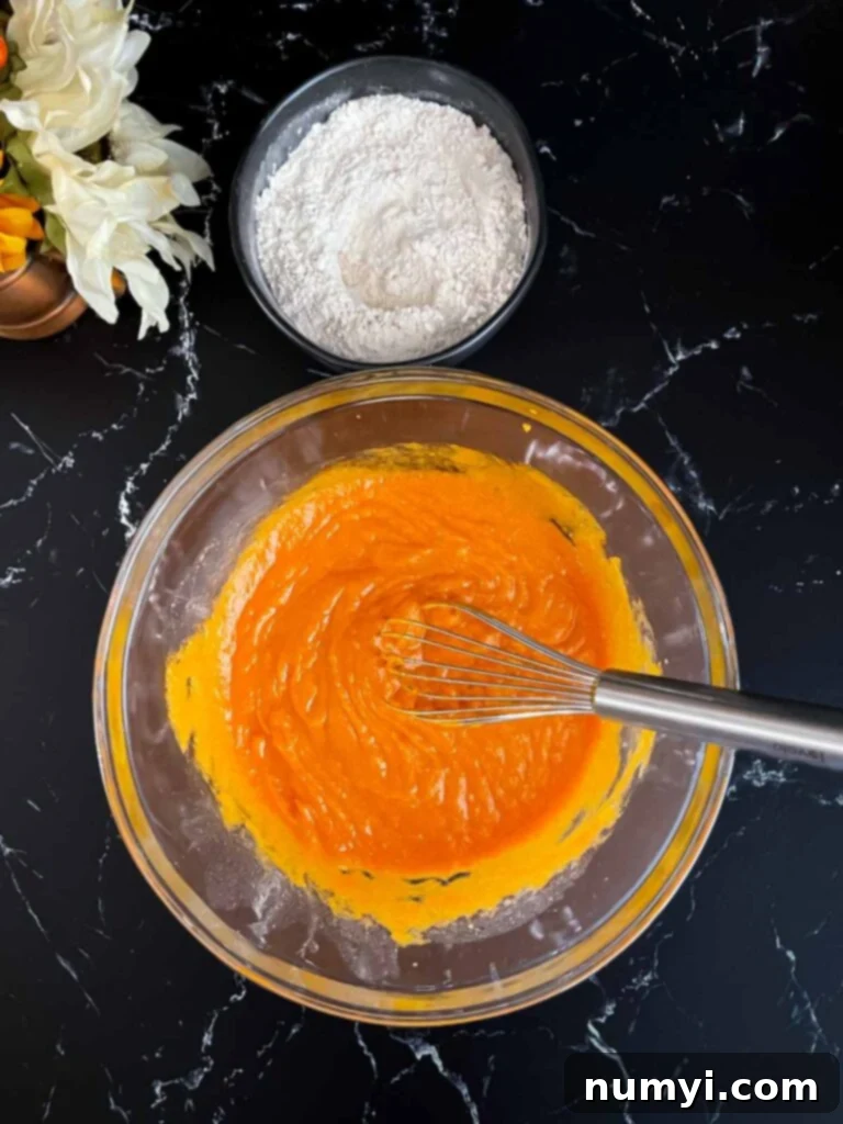 Two bowls: one with dry ingredients for muffins and another with wet pumpkin and egg mixture, ready to be combined.