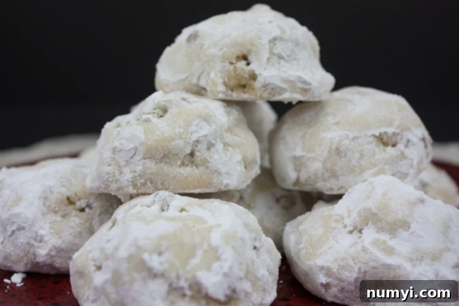 Italian Butterball Cookies stacked on a red plate, dusted with powdered sugar.