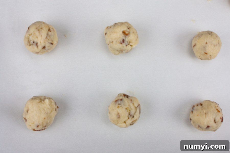 Italian Butterball Cookie dough balls arranged on a parchment-lined baking sheet before baking.