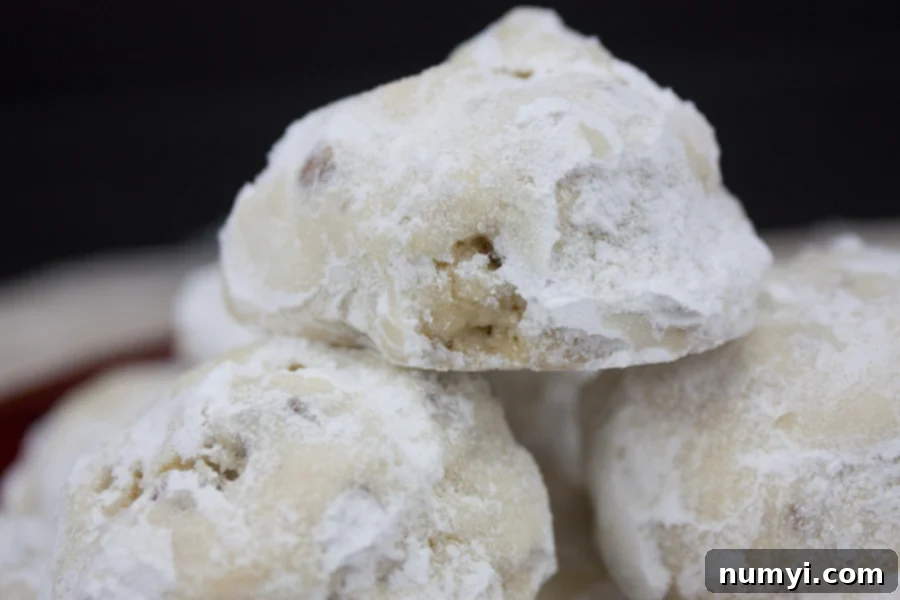 Beautifully stacked Italian Butterball Cookies, perfectly dusted with powdered sugar, on a decorative plate.