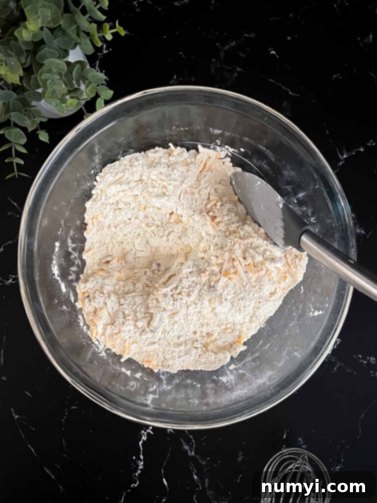 Shredded cheddar cheese stirred into the dry ingredients for bacon cheddar biscuits recipe.