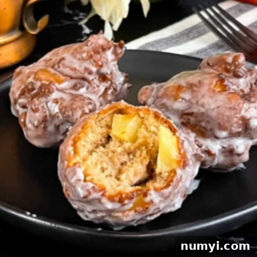 Sweet Apple Puffs 11 Apple fritters on a dark plate on a dark surface.