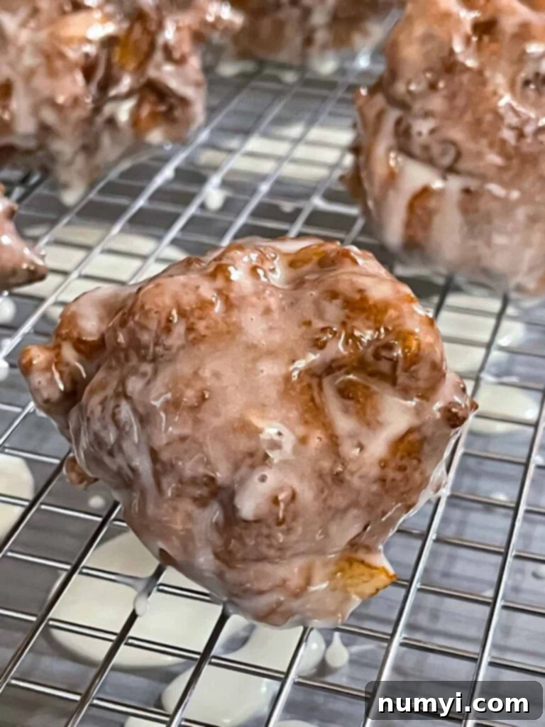 Sweet Apple Puffs 10 Glazed apple fritters on a wire rack over a baking sheet.