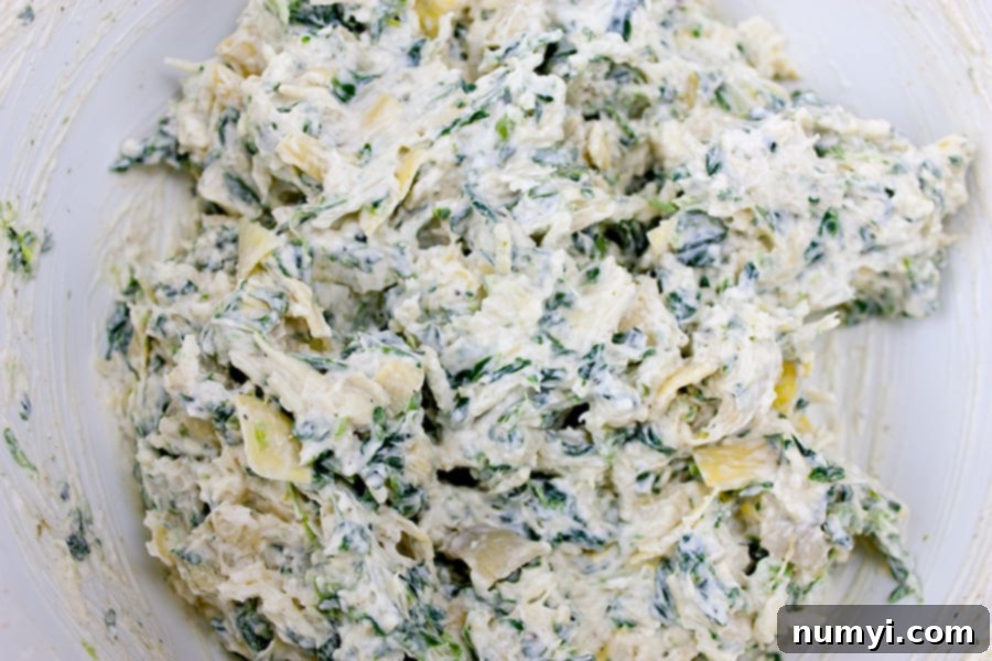 Creamy Spinach Artichoke Bites 3 Spinach Artichoke Cups filling combined in a white mixing bowl, showing the creamy texture.