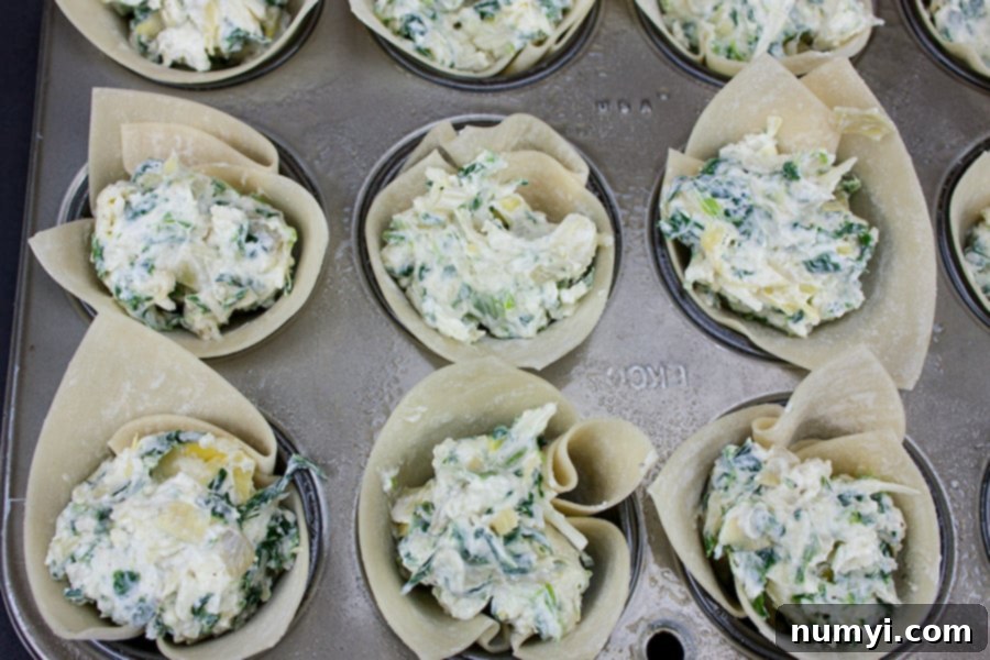 Creamy Spinach Artichoke Bites 5 Spinach Artichoke Cups - wontons in a mini muffin pan stuffed with filling, ready for baking.