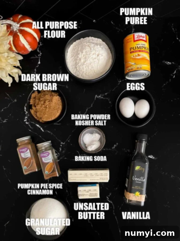 Baked pumpkin donuts recipe ingredients laid out on a dark surface, including pumpkin puree, spices, flour, and eggs.