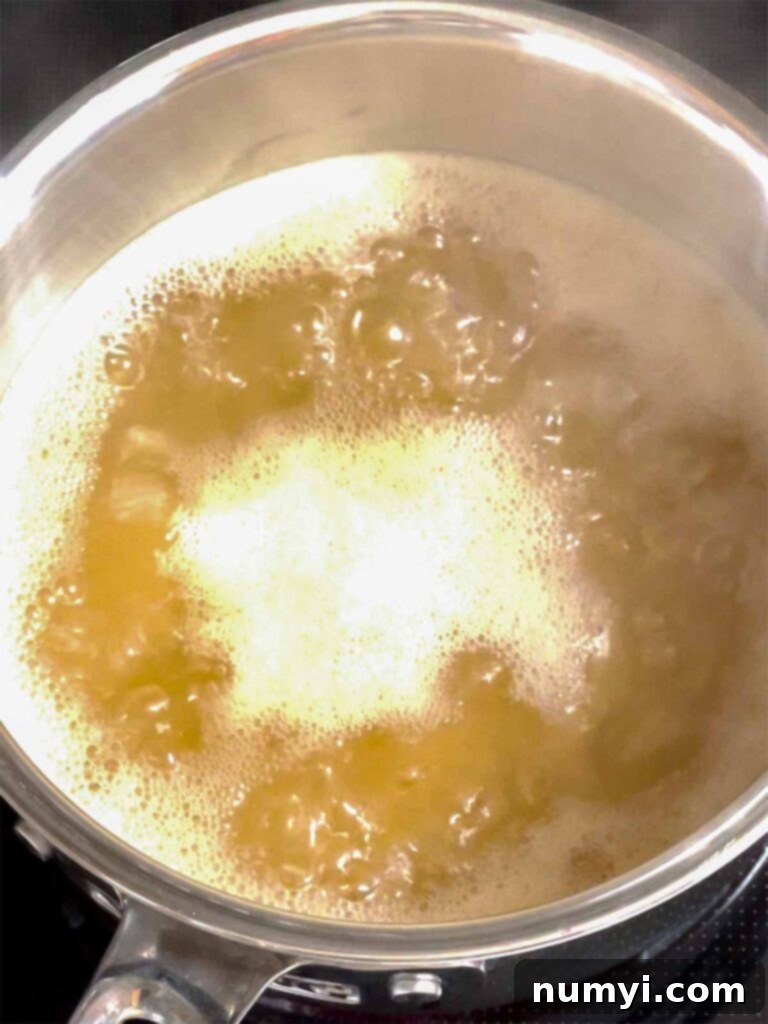 Apple cider boiling in a small sauce pan.