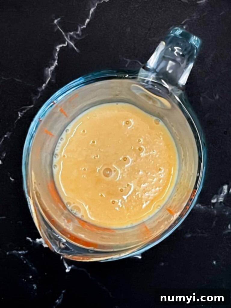 Buttermilk, vanilla extract, and reduced apple cider mixed in a glass measuring cup.